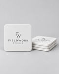 Illustrative business mockup. Matching white coaster set with Fieldwork Studio logos