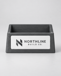 Illustrative business mockup. Charcoal business card holder with Northline Build Co. logo plate