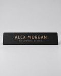 Illustrative business mockup. Black wooden Alex Morgan desk nameplate with tan engraving