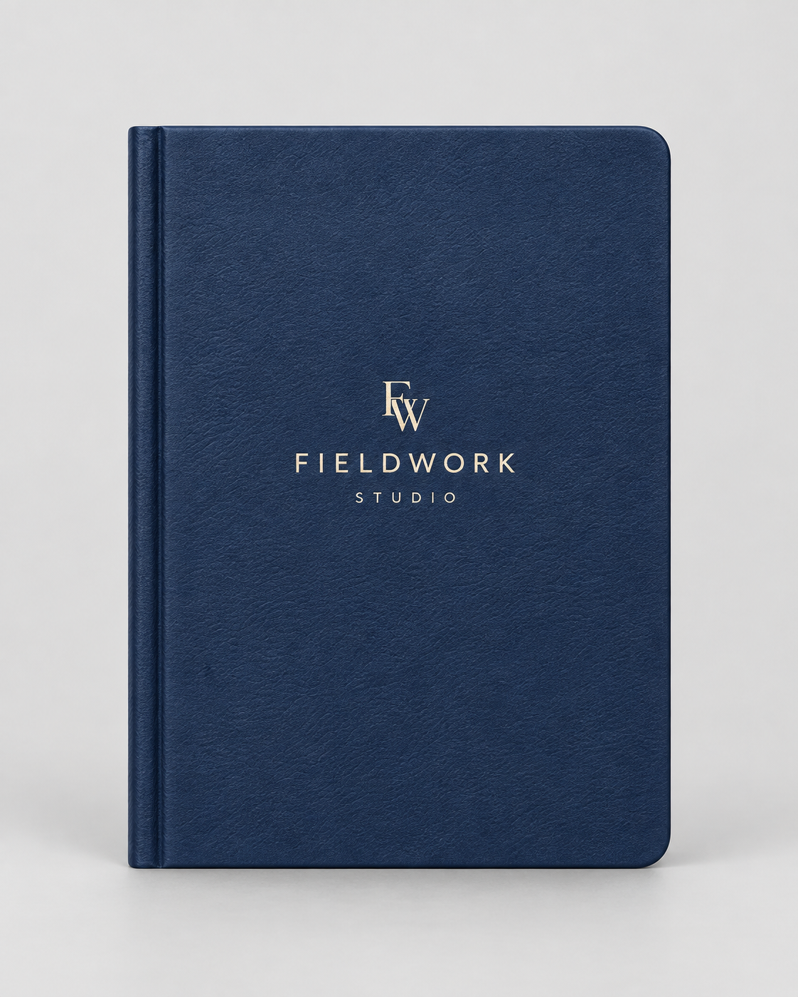 Illustrative business mockup. Navy notebook with cream Fieldwork Studio cover logo