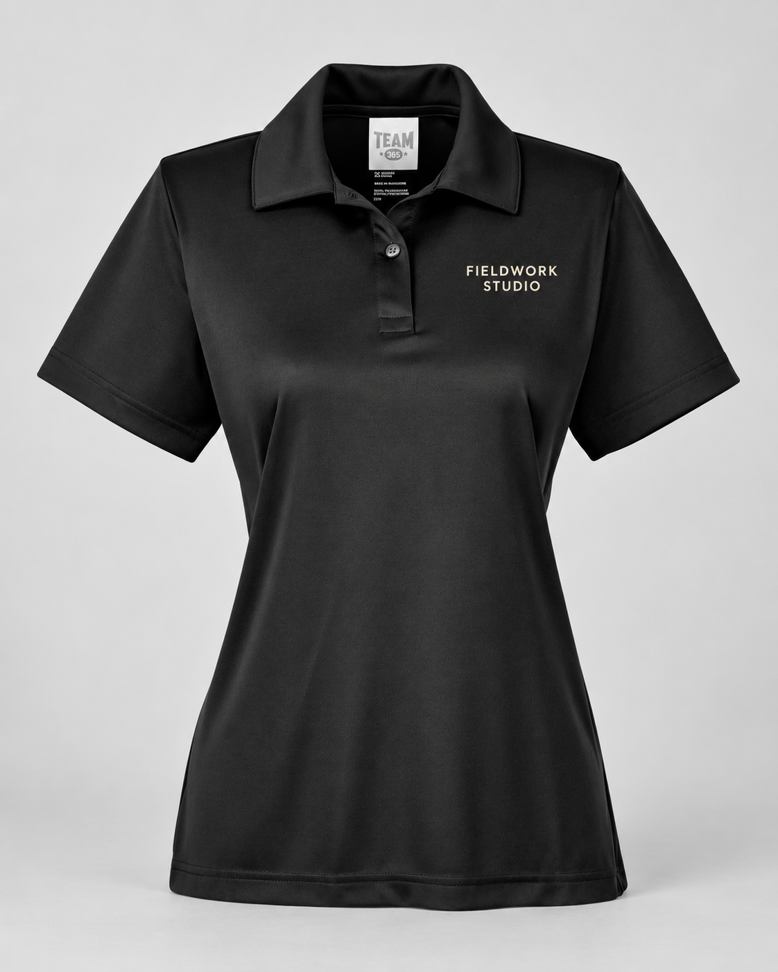 Illustrative business mockup. Team 365 TT51W Women’s performance polo with a small professional business logo on a neutral studio background